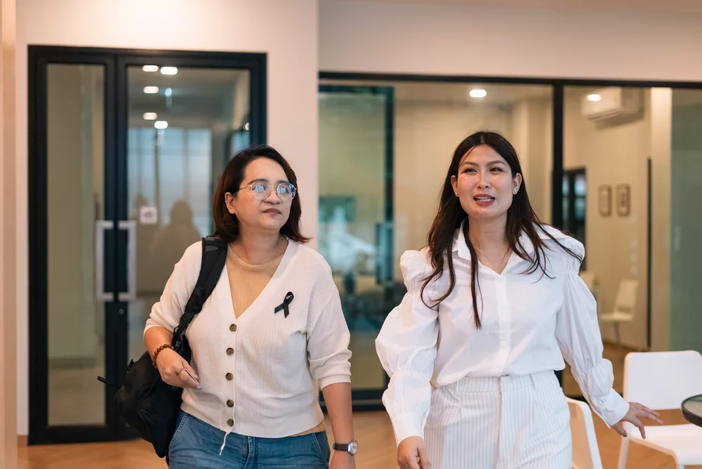 Dua profesional berjalan bersama di kantor